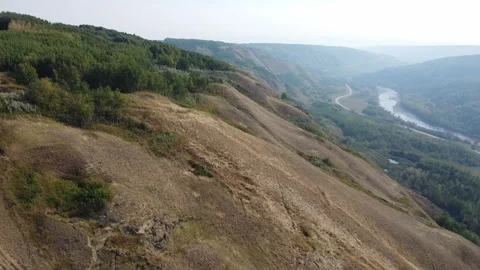 Drone overlooking large river valley with rolling hills on sunny day Stock Footage 255866690