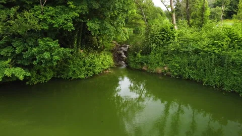Drone pan out of waterfall above lake Stockbeeldmateriaal 155574403