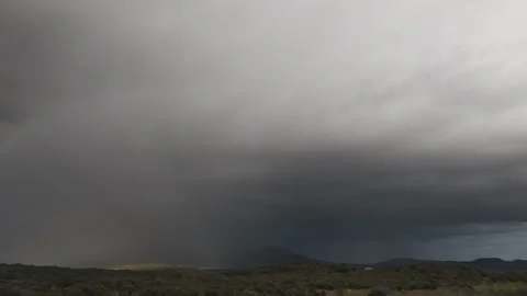 Drone pan revealing rainbow and storm clouds over mountains at 70mm Video stock 339067970
