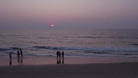 Drone pan view of people enjoying beach sunset with waves and relaxing coas.. Stock Footage 340967023