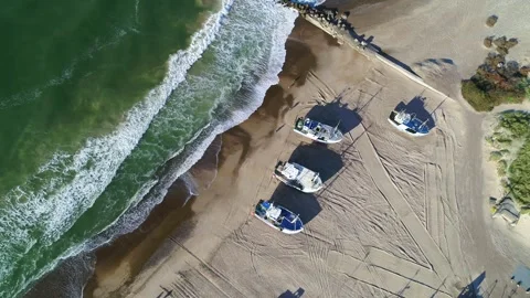 Drone panning around over sandy beach with fishing boats docked on the beach Stock Footage 305565223