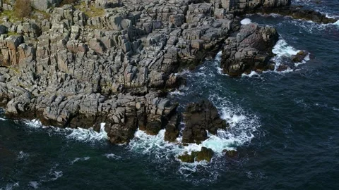 Drone panning around small waves crashing on a rocky shore Stock Footage 314213638