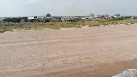 Drone panning shot along with beach houses on the sand in united kingdom Stock Footage 141463092