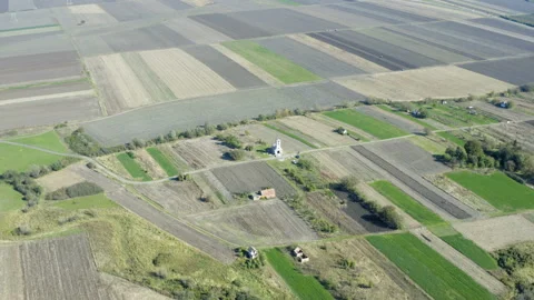 Drone panorama in motion of agricultural fields which approaches the church Stockbeeldmateriaal 141524152