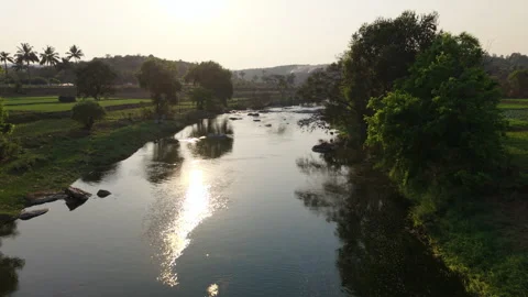 Drone Panoramic shot over a river flowing next to fields in rural India Stock Footage 305268141