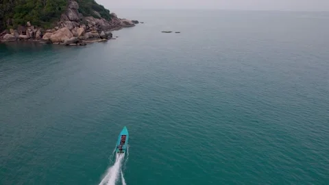 Drone pans down camera to a boat in the ocean heading to Eden Party, Koh Phangan Stock Footage 277401839