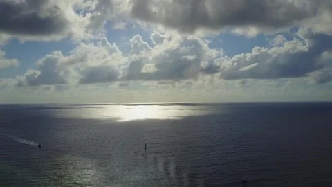 Drone pans high over ocean with sunshine reflecting in the distance. 스톡 동영상 244822829