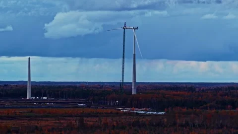 Drone parallax view of renewable wind power infrastructure beneath threatening Stock Footage 329142893