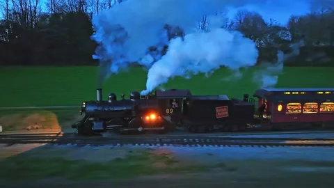 A Drone Parallel Night View of a Steam Passenger Train Starts Up Blowing Video stock 226328923