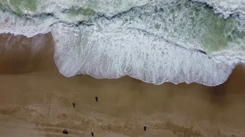 The drone passes over the foamy waves as it moves from the beach to the sea. Stock Footage 246709959