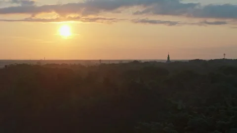 Drone passes over a forest at sunrise, silhouetted city towers and chimneys.. Stock-Footage 284922049