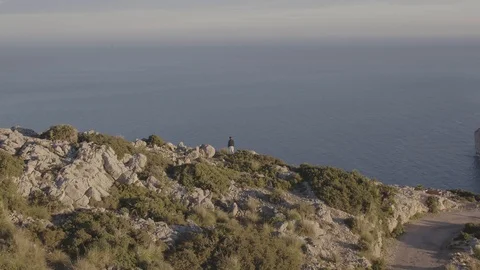 Drone passes over man standing on cliff of Formentor, Mallorca with INSPIRE 2 Stock Footage 101428516