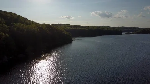Drone passes over reflecting spring lake framed by forest in Connecticut Stock Footage 90139536