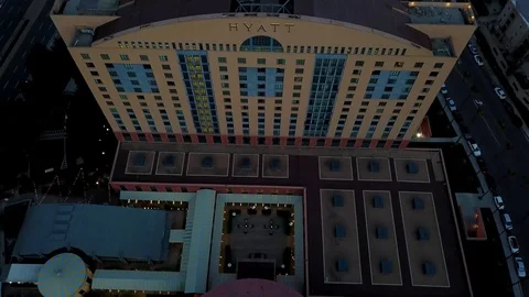 Drone passes over tall odd shaped Hyatt hotel at dusk with cam straight down Stock Footage 97181960