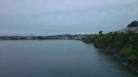 Drone passing between rock and coast advancing over water 스톡 동영상 340992962