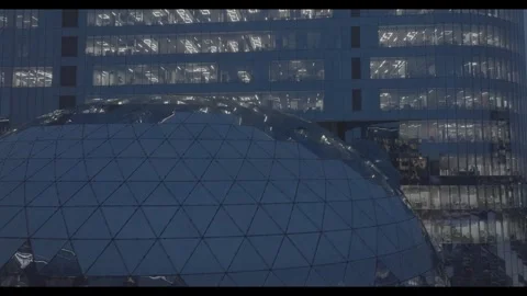 Drone passing glass dome under illuminated office tower Stock Footage 320182707
