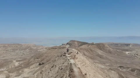 Drone passing through people with mountain bikes on a sharp ridge, desert 스톡 동영상 239760554