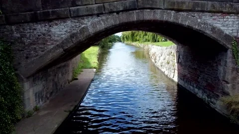 Drone Passing Under an Old Stone Bridge on a UK Canal Stock Footage 138507714