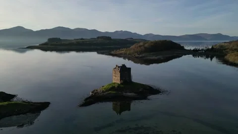 Drone pausing, then moving slightly backward from island castle in Scotland 動画素材 334459078