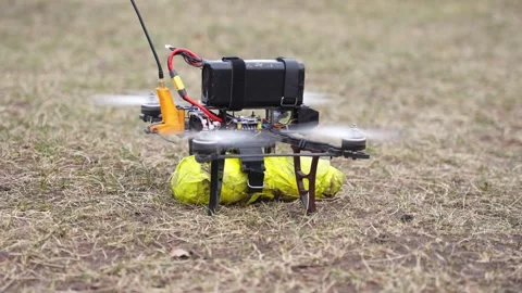 Drone with payload attachment hovering over training field Stock Footage 334696014