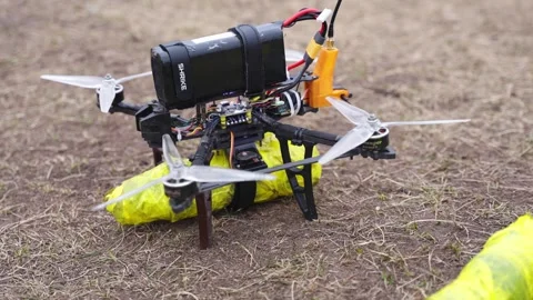 Drone with payload system hovering low over dirt training ground Stock Footage 334695958