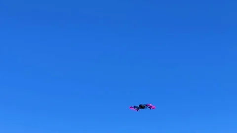 Drone performing a side flip stunt in the air with blue sky in the Stock Footage 113422789
