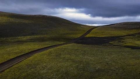 Drone perspective of a black paved road curving through moss-covered volcanic Stock Photos