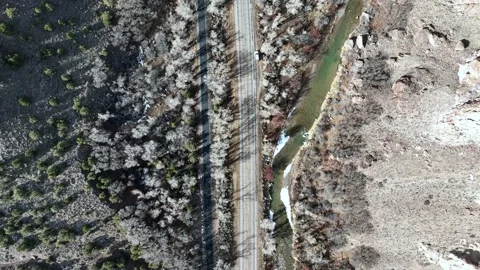 Drone perspective of highway road next to river in a rocky mountain canyon Stock Footage 229807475