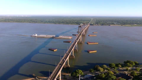 Drone perspective of the Paraná River showing barge traffic beneath the General Stock-Footage 320978390