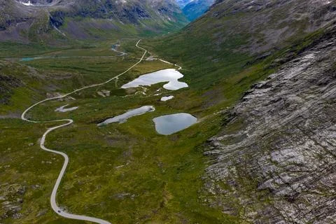 Drone perspective of U-shaped glacial valley with serpentine mountain road, m Stock Photos