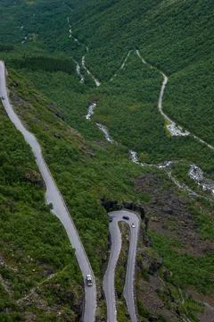Drone perspective of winding mountain highway cutting through dense green for Фото