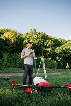 A drone pilot configuring his drone in a field with and irrigation system bef Stock Photos
