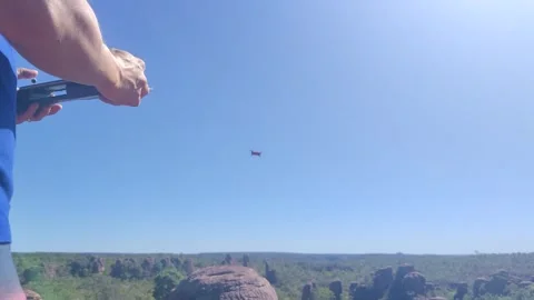 Drone pilot flying a quadcopter over a vast scenic landscape. 스톡 동영상 312898011