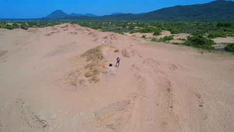 Drone pilot focus on his controller during dronie from desert beach Stock Footage 162461118