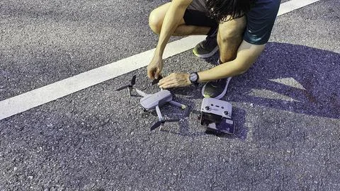 Drone pilot preparing quadcopter before flight on asphalt road Stock Photos