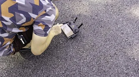 Drone pilot preparing quadcopter before flight on asphalt road Stock Photos