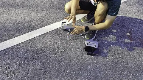 Drone pilot preparing quadcopter before flight on asphalt road Stock Photos