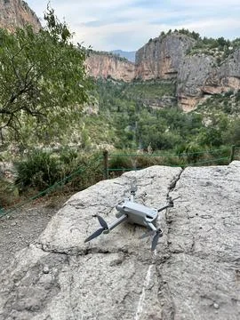Drone placed on rock with canyon cliffs and green valley Stock Photos