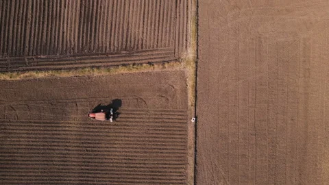Drone point of view farmer driving tractor crop planting machine in field Stock Footage 226726580