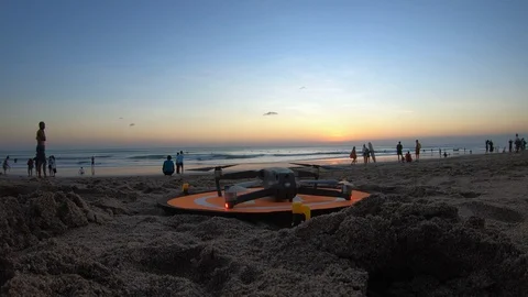 The drone is preparing to take off on the beach near the ocean at sunset day. Stock Footage 113963518