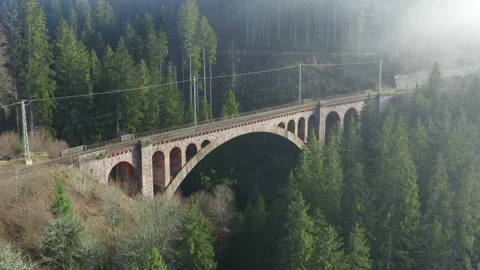 Drone pull away from historic stone railway viaduct revealing forest valley Vídeos de archivo 323866420