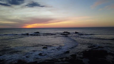 Drone pull away shot of rocky beach and ocean waves at sunset. Stock Footage 331870006