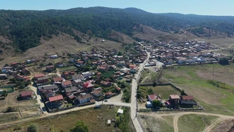 Drone pull back over Banya village and pine forest hills in Bulgaria Stock Footage 346494697