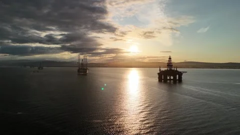 Drone pull back over oil rig graveyard at sunset in Cromarty Firth Stock Footage 330675614