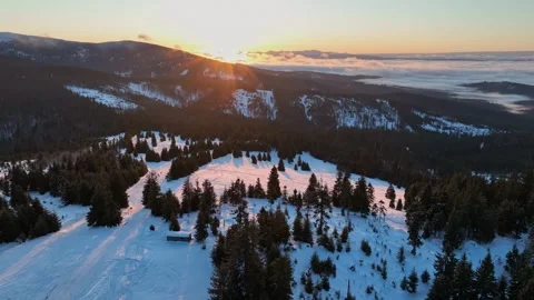 Drone pull back over sunlit winter meadow with tourists silhouettes Stock Footage 336446159