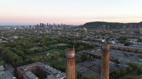 Drone pull-back revealing Montreal skyline and factory chimneys at sunset Stock Footage 317558753