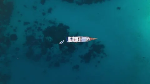 Drone pull-back shot of boat over vibrant blue ocean 스톡 동영상 332615268