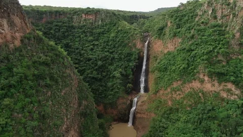 Drone pull back shot at El Salto del Nogal waterfall between lush canyon cliffs Stock Footage 335971123