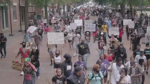 Drone pull back from street view of massive crowd of people marching with Stock Footage 142382627