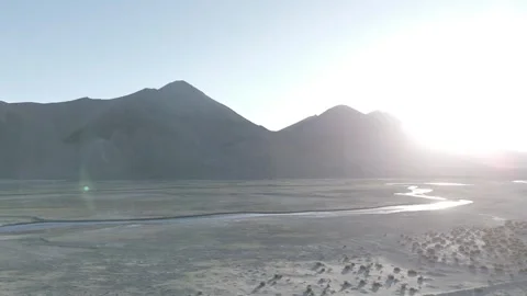 Drone Pull Out Over Dry Ladakh River Landscape with Backlit Mountain Sunlight Stock-Footage 335760782